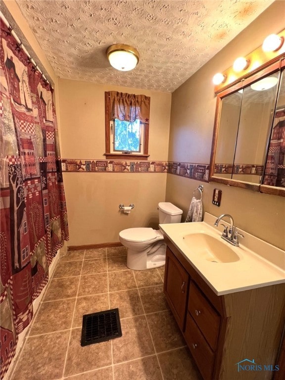 bathroom featuring vanity, toilet, a textured ceiling, and tile patterned flooring