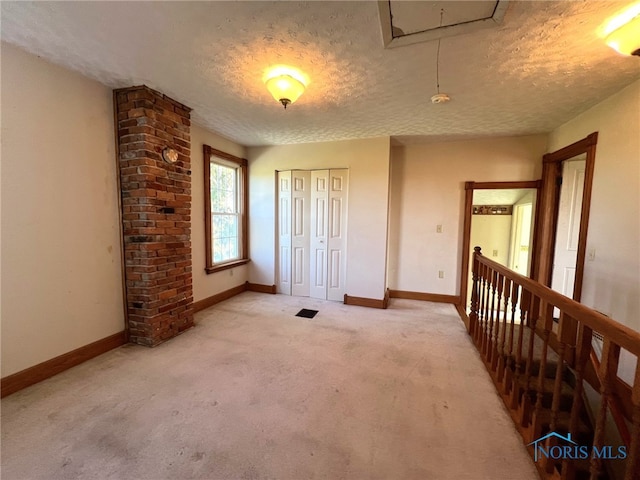 carpeted empty room featuring a textured ceiling