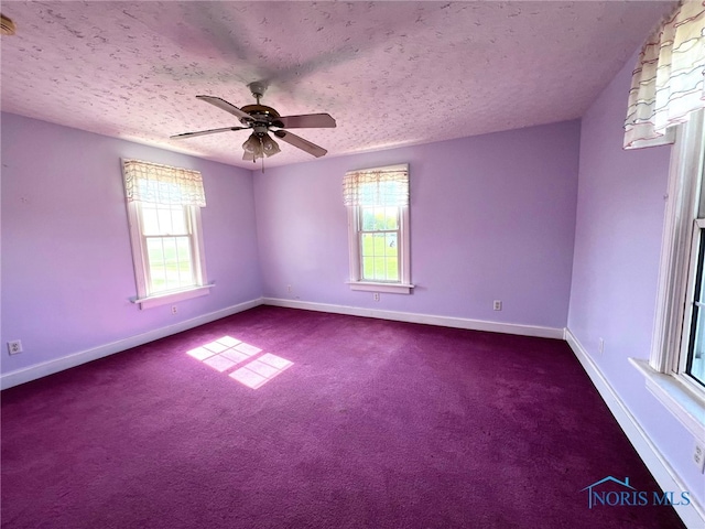 carpeted empty room with ceiling fan, a textured ceiling, and plenty of natural light