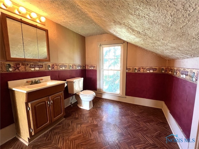 bathroom with lofted ceiling, a textured ceiling, toilet, parquet floors, and vanity