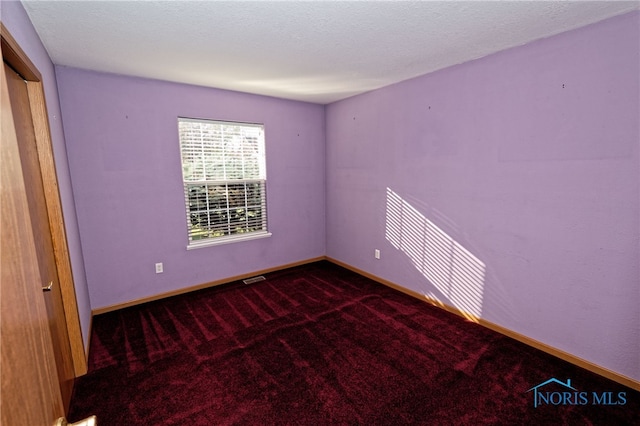 empty room featuring a textured ceiling and carpet