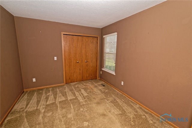 unfurnished bedroom with a closet, a textured ceiling, and carpet