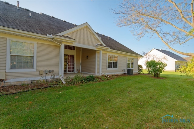 back of property featuring central air condition unit and a lawn