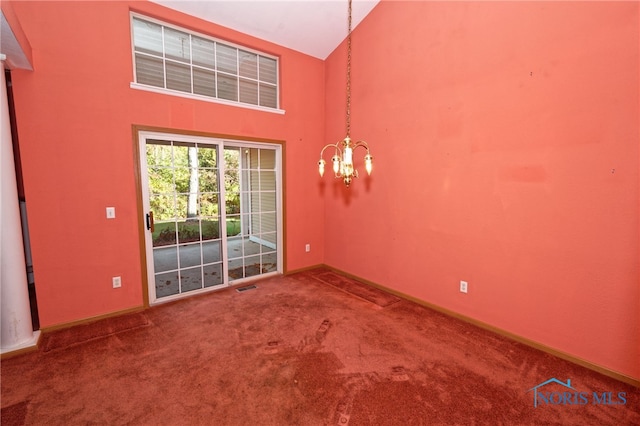 carpeted empty room with a chandelier and high vaulted ceiling