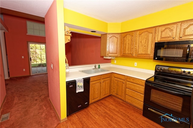 kitchen with light hardwood / wood-style flooring, black appliances, and sink