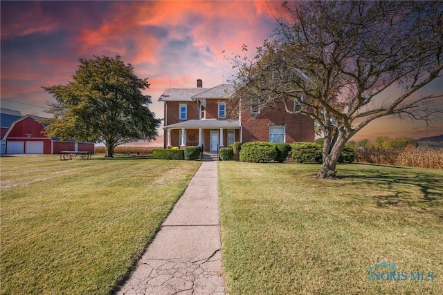 colonial-style house featuring a lawn and covered porch