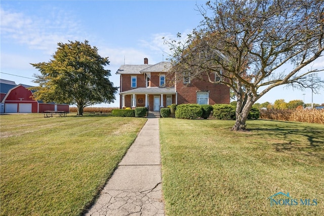 colonial-style house with covered porch, an outbuilding, and a front lawn