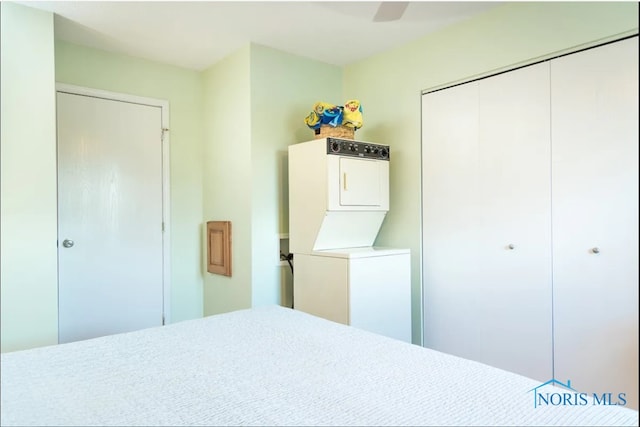 bedroom with stacked washer and clothes dryer, a closet, and ceiling fan