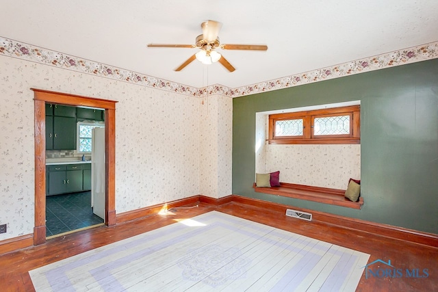 unfurnished bedroom featuring ceiling fan, ensuite bath, and dark hardwood / wood-style floors