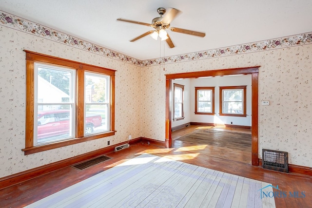 unfurnished room with dark wood-type flooring, ceiling fan, and plenty of natural light