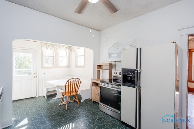 kitchen with a wealth of natural light, a textured ceiling, white appliances, and ceiling fan