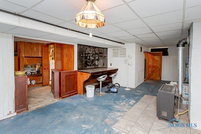 basement featuring washer / dryer, a drop ceiling, and wood walls