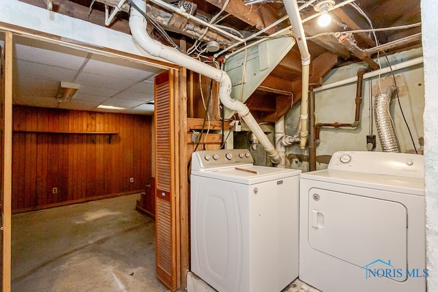 laundry room with wood walls and washing machine and clothes dryer