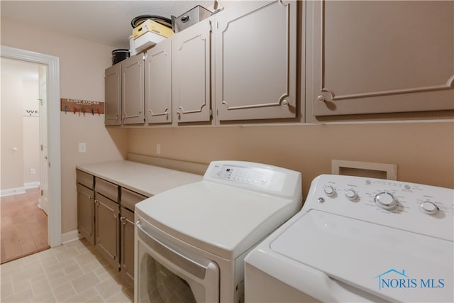 washroom with washer and clothes dryer, light hardwood / wood-style flooring, and cabinets