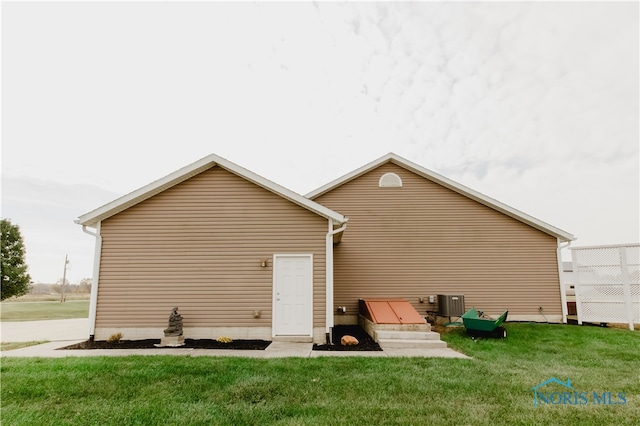 rear view of house featuring a yard and central AC unit