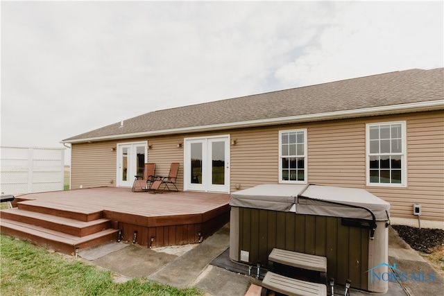 rear view of property with a hot tub, french doors, and a deck