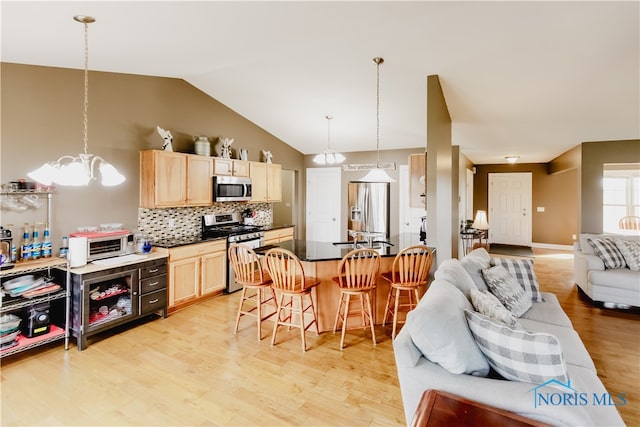 kitchen featuring light brown cabinets, a kitchen breakfast bar, light hardwood / wood-style flooring, pendant lighting, and stainless steel appliances