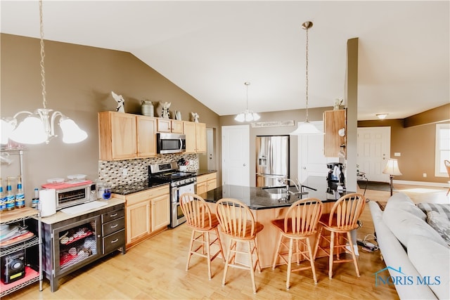 kitchen featuring a chandelier, a kitchen bar, stainless steel appliances, and light wood-type flooring