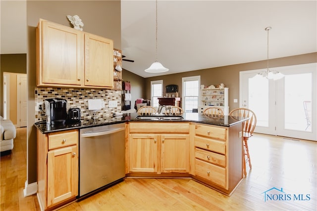 kitchen with stainless steel dishwasher, vaulted ceiling, and hanging light fixtures