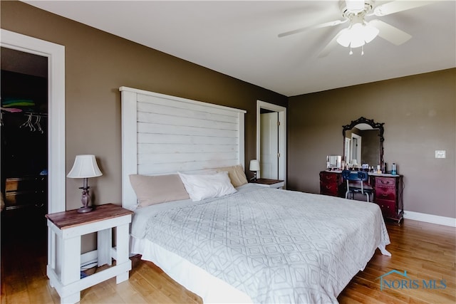 bedroom featuring a spacious closet, a closet, hardwood / wood-style flooring, and ceiling fan