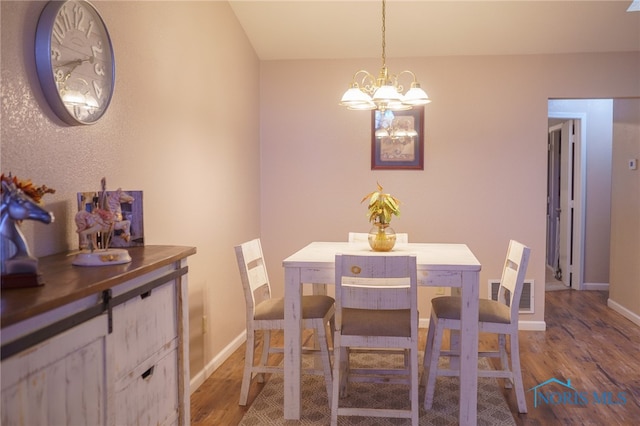 dining space with hardwood / wood-style floors and an inviting chandelier