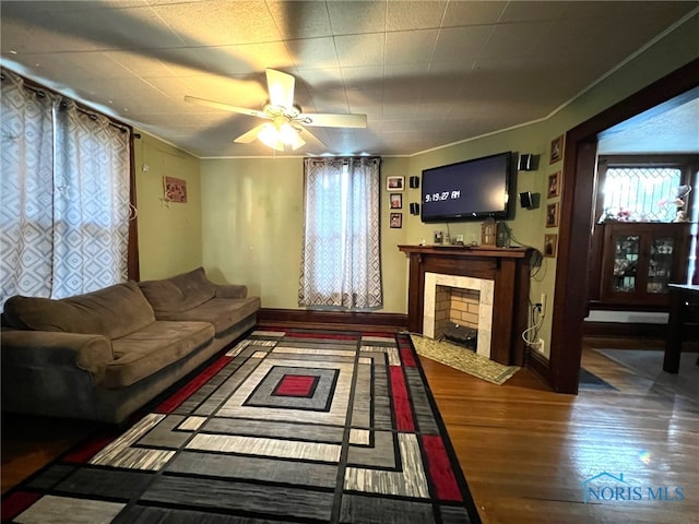 living room with a wealth of natural light, hardwood / wood-style flooring, ceiling fan, and a tile fireplace