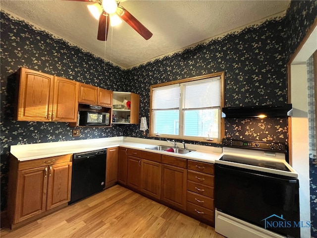 kitchen with a textured ceiling, light hardwood / wood-style floors, black appliances, and sink