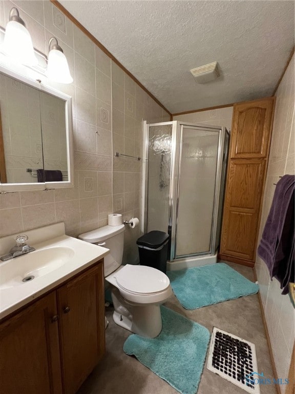 bathroom with tile walls, vanity, a textured ceiling, and a shower with door