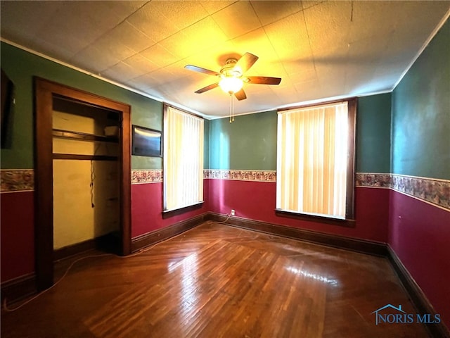 unfurnished bedroom featuring dark hardwood / wood-style flooring, ceiling fan, and crown molding