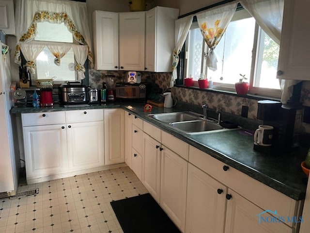 kitchen with white cabinetry, tasteful backsplash, and sink