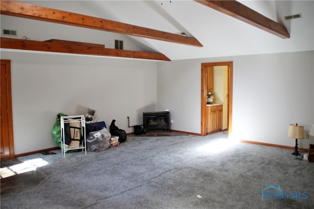 living room featuring a wood stove, lofted ceiling with beams, and carpet flooring