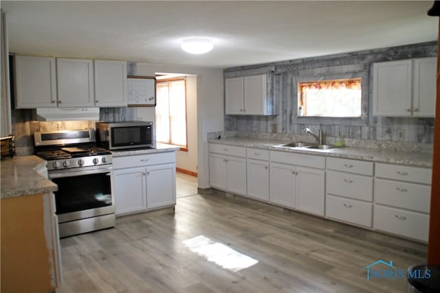 kitchen featuring stainless steel appliances, backsplash, sink, light wood-type flooring, and white cabinetry