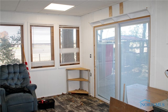 doorway to outside featuring a wealth of natural light, a paneled ceiling, and wood walls