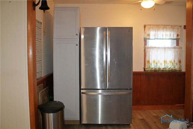 kitchen featuring ceiling fan, wood walls, dark hardwood / wood-style floors, and stainless steel fridge