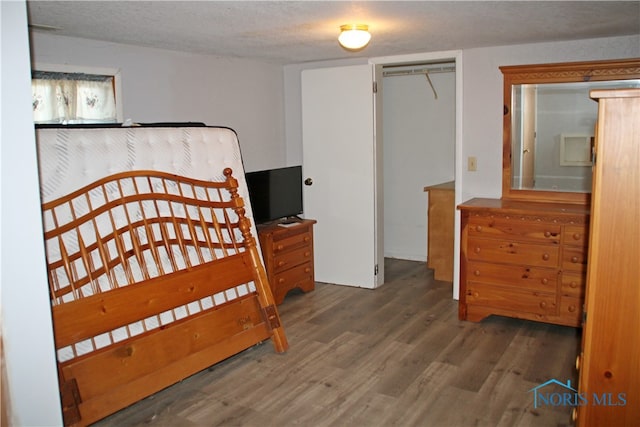 bedroom with a closet, dark wood-type flooring, and a textured ceiling