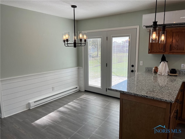 unfurnished dining area featuring a baseboard heating unit, a textured ceiling, a wall unit AC, a notable chandelier, and dark hardwood / wood-style floors