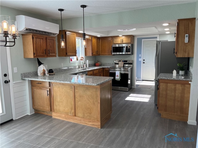 kitchen with a wall unit AC, kitchen peninsula, stainless steel appliances, sink, and dark hardwood / wood-style flooring