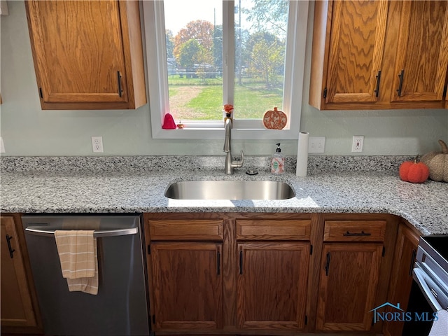 kitchen featuring appliances with stainless steel finishes, light stone counters, and sink