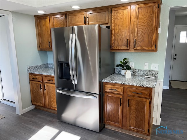 kitchen featuring light stone counters, stainless steel refrigerator with ice dispenser, and dark hardwood / wood-style flooring