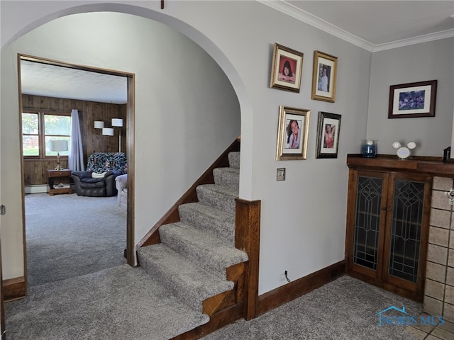 staircase featuring carpet, wood walls, ornamental molding, and a baseboard radiator