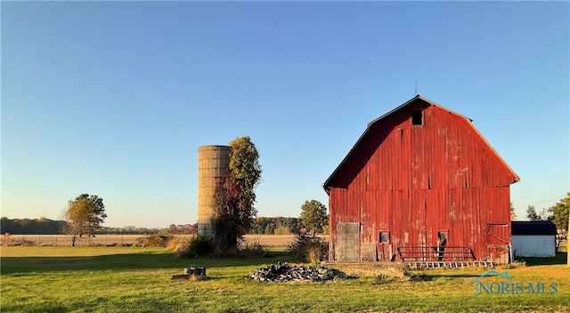 view of outbuilding featuring a rural view and a lawn