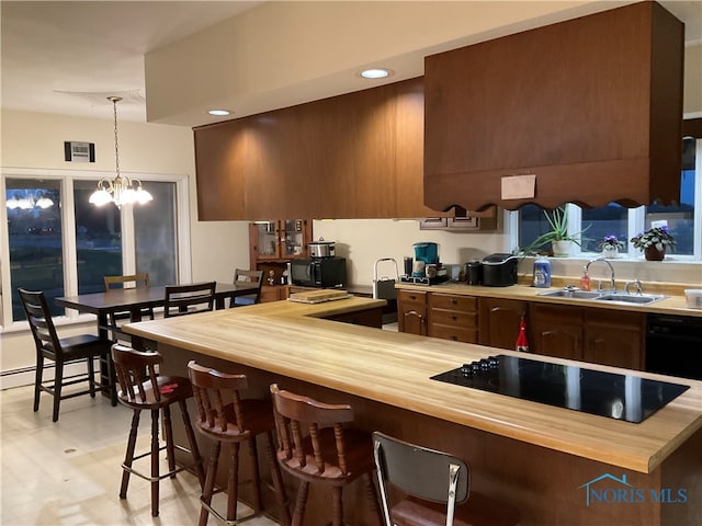 kitchen featuring black appliances, a kitchen bar, a notable chandelier, hanging light fixtures, and sink