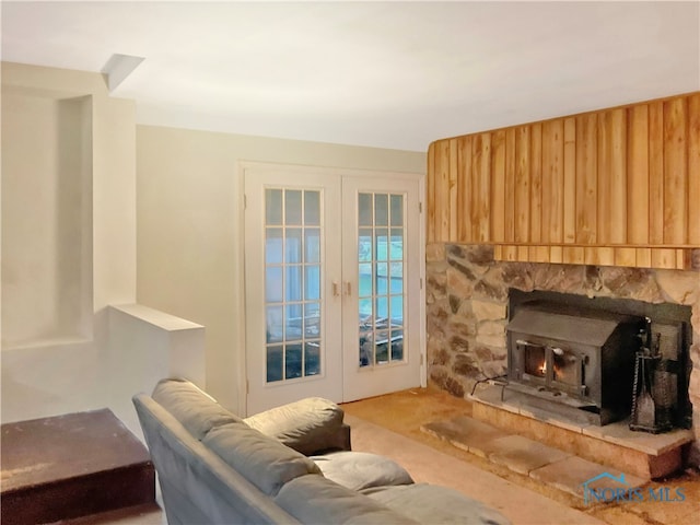 carpeted living room with a wood stove, french doors, and wooden walls