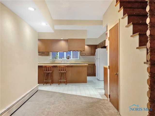 kitchen with sink, kitchen peninsula, a baseboard heating unit, light colored carpet, and white fridge