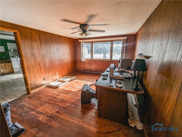 office area featuring washer / clothes dryer, wooden walls, hardwood / wood-style floors, a baseboard radiator, and ceiling fan