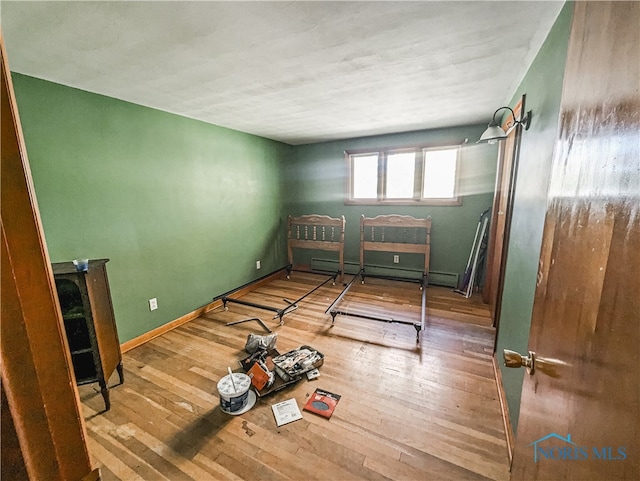 unfurnished bedroom featuring hardwood / wood-style floors and baseboard heating