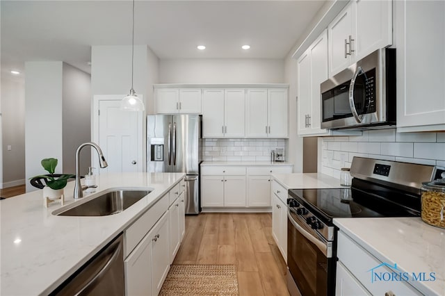 kitchen featuring appliances with stainless steel finishes, sink, decorative light fixtures, and white cabinets