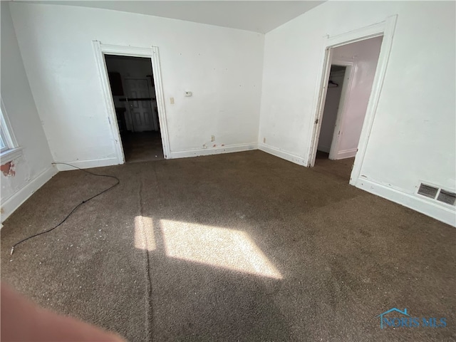 unfurnished room featuring dark carpet