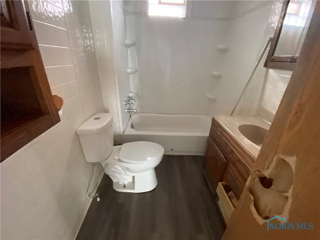 full bathroom featuring toilet, hardwood / wood-style floors, vanity, and tile walls