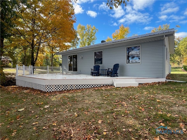 back of property featuring a deck and a lawn